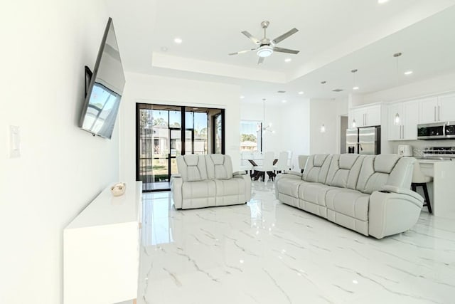 living room with ceiling fan and a tray ceiling