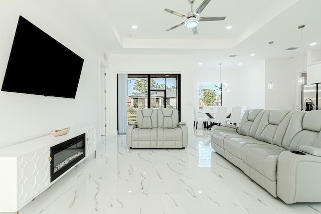 living room featuring a raised ceiling and ceiling fan