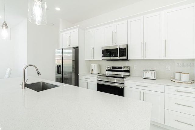 kitchen with decorative light fixtures, white cabinets, sink, and stainless steel appliances