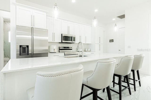 kitchen featuring stainless steel appliances, pendant lighting, white cabinets, and sink