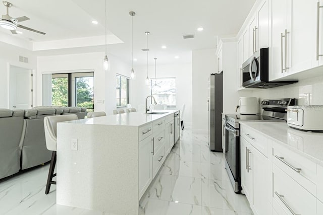 kitchen with white cabinetry, an island with sink, appliances with stainless steel finishes, a kitchen breakfast bar, and sink