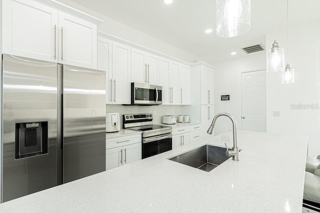 kitchen featuring white cabinetry, appliances with stainless steel finishes, decorative light fixtures, light stone countertops, and sink