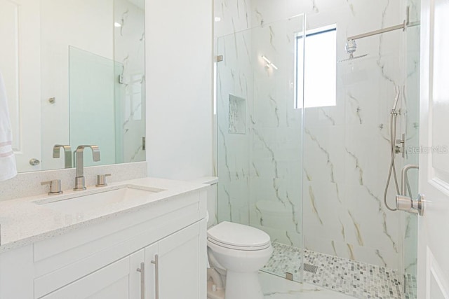 bathroom featuring toilet, a shower with shower door, and vanity