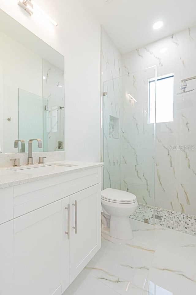 bathroom featuring toilet, vanity, and tiled shower