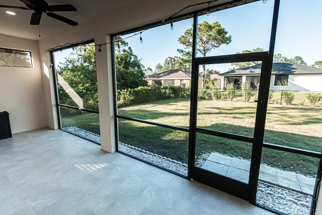 unfurnished sunroom featuring ceiling fan and a wealth of natural light