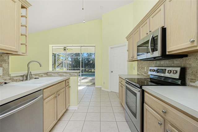 kitchen featuring lofted ceiling, sink, light tile patterned floors, light brown cabinetry, and appliances with stainless steel finishes