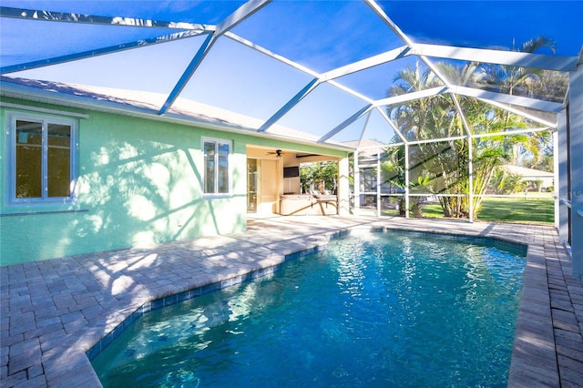 view of swimming pool with glass enclosure, ceiling fan, and a patio area