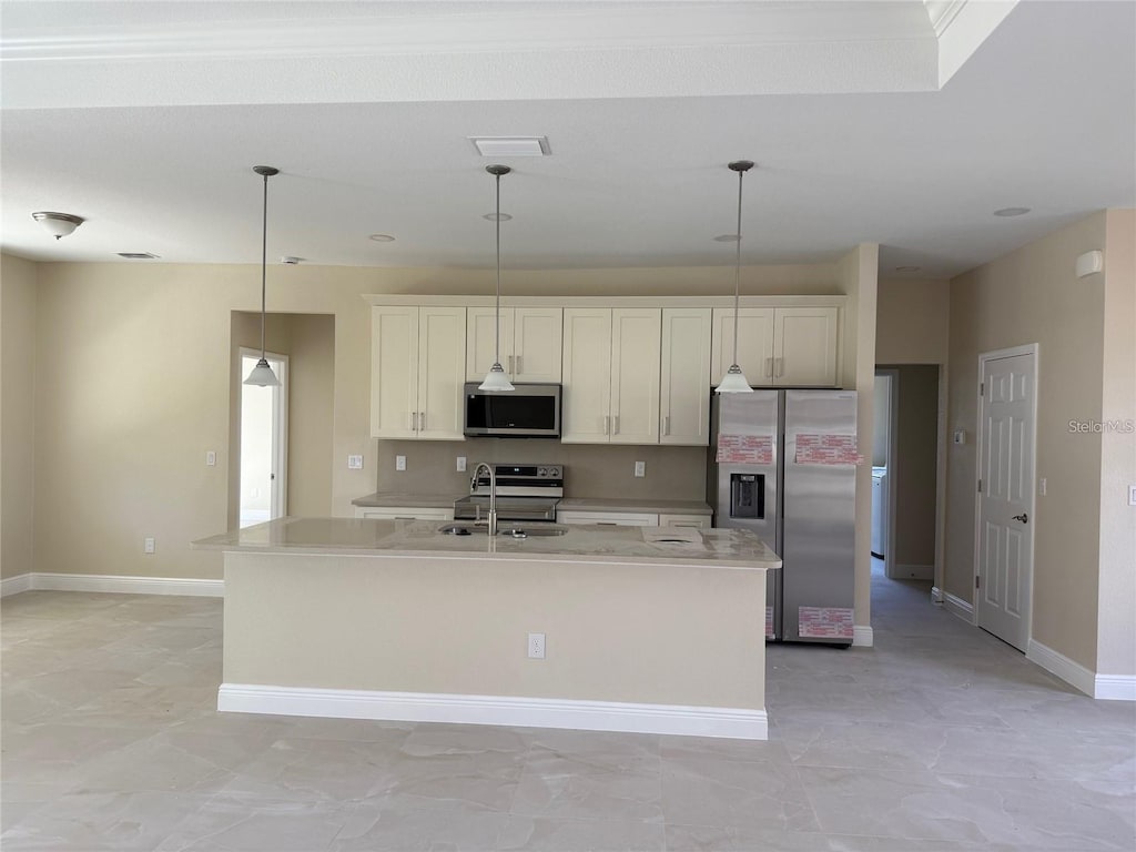 kitchen featuring pendant lighting, sink, stainless steel appliances, and a kitchen island with sink