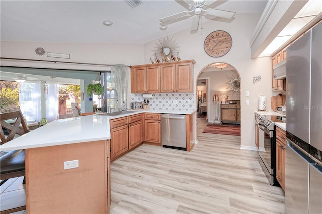 kitchen featuring a breakfast bar, stainless steel appliances, sink, light hardwood / wood-style floors, and lofted ceiling