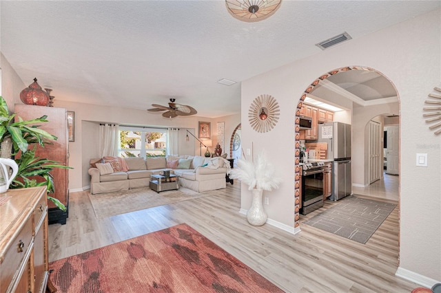 living room featuring a textured ceiling, light hardwood / wood-style flooring, and ceiling fan