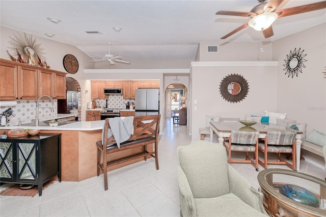 interior space with sink, stainless steel appliances, backsplash, vaulted ceiling, and light tile patterned floors