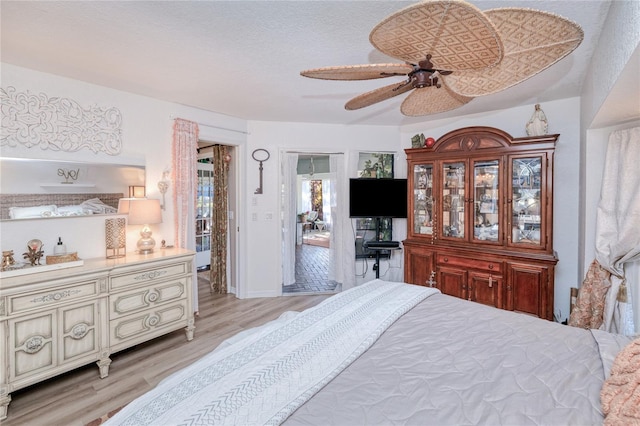 bedroom with a textured ceiling, light wood-type flooring, and ceiling fan