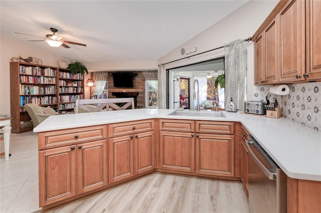 kitchen with kitchen peninsula, backsplash, stainless steel dishwasher, sink, and light hardwood / wood-style floors