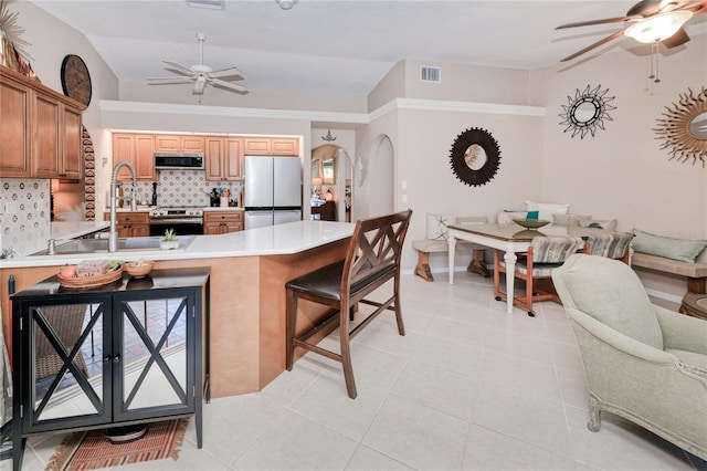 kitchen with lofted ceiling, decorative backsplash, light tile patterned floors, appliances with stainless steel finishes, and a breakfast bar area