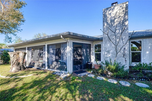 rear view of property with a sunroom and a yard