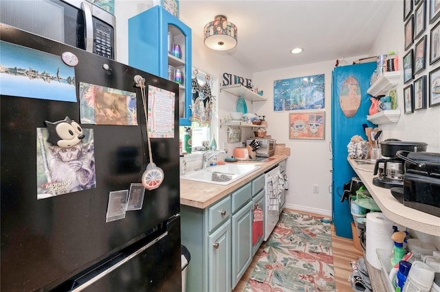 kitchen featuring wooden counters, light wood-type flooring, black fridge, stainless steel dishwasher, and sink