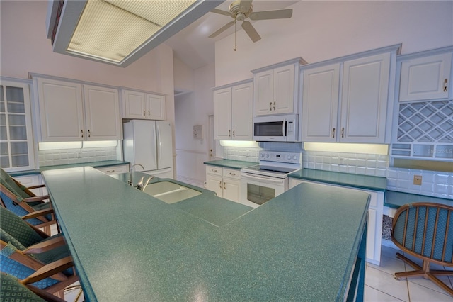 kitchen featuring white appliances, backsplash, high vaulted ceiling, and sink