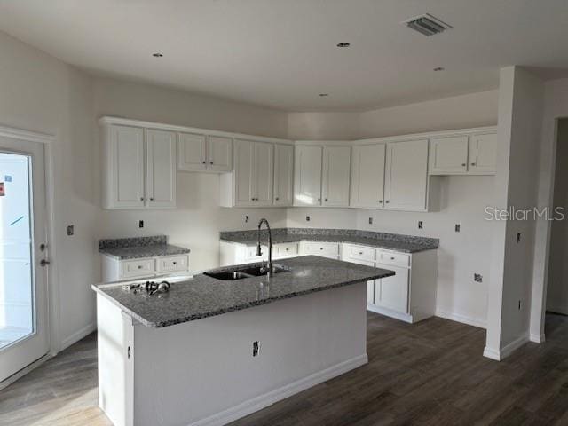 kitchen with sink, dark hardwood / wood-style floors, white cabinetry, and an island with sink