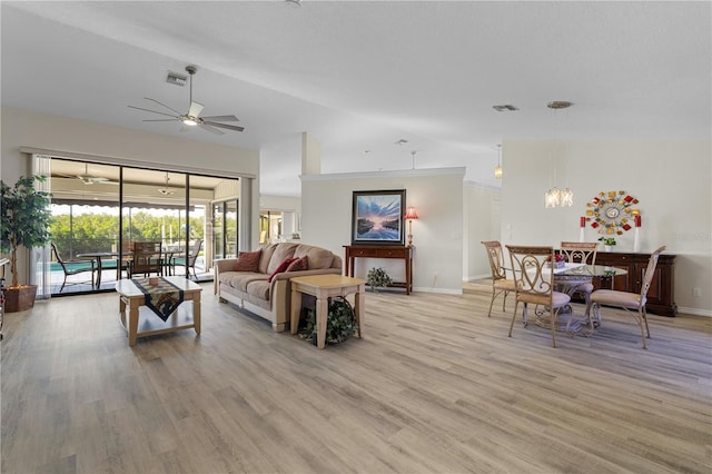 living room featuring lofted ceiling, light hardwood / wood-style floors, and ceiling fan with notable chandelier