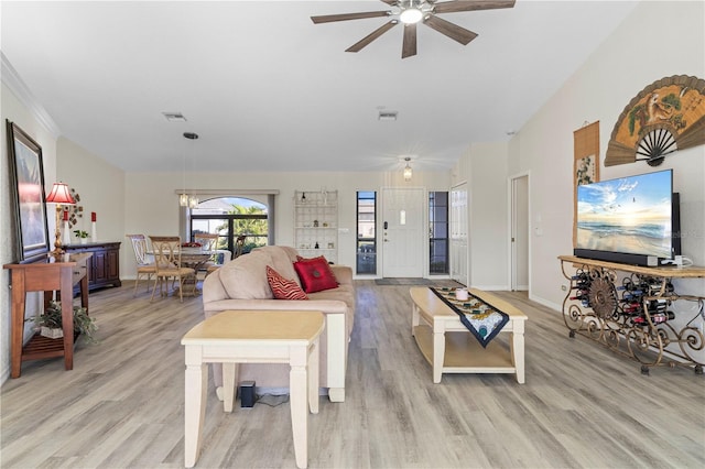 living room featuring ceiling fan with notable chandelier and light wood-type flooring