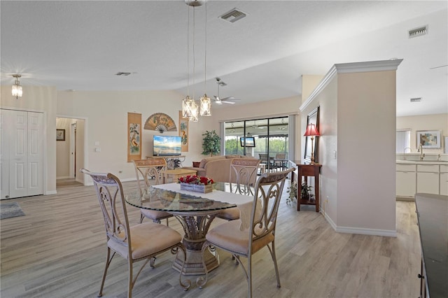 dining space with ceiling fan with notable chandelier, vaulted ceiling, and light hardwood / wood-style flooring