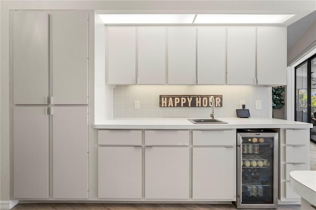 kitchen with tasteful backsplash, wine cooler, white cabinetry, and sink