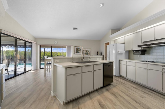 kitchen with black appliances, sink, vaulted ceiling, decorative backsplash, and an island with sink