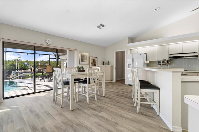 dining space featuring light hardwood / wood-style flooring and vaulted ceiling