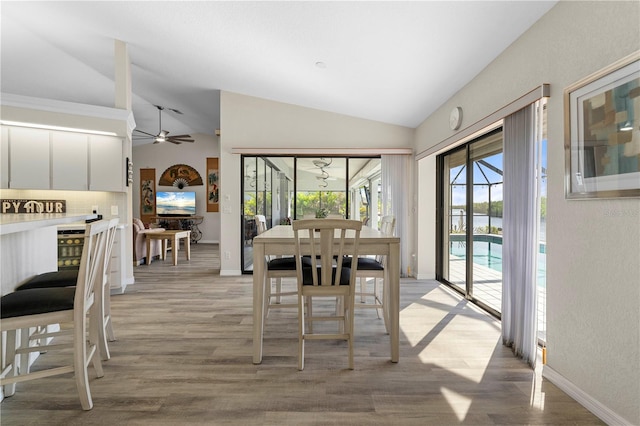 dining space with ceiling fan, wood-type flooring, and vaulted ceiling