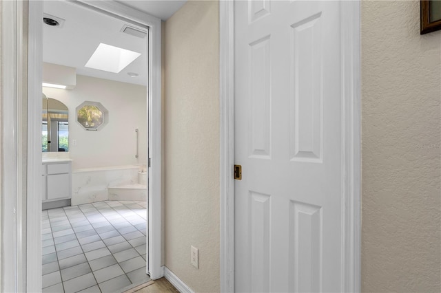 hall featuring a skylight and light tile patterned floors