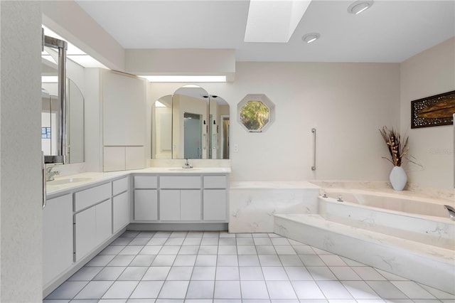 bathroom with a skylight, a wealth of natural light, a bathtub, vanity, and tile patterned flooring