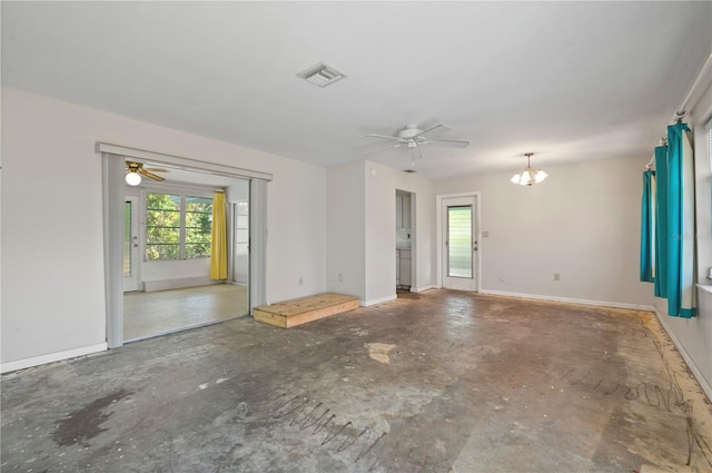 spare room featuring ceiling fan with notable chandelier, a wealth of natural light, and concrete flooring