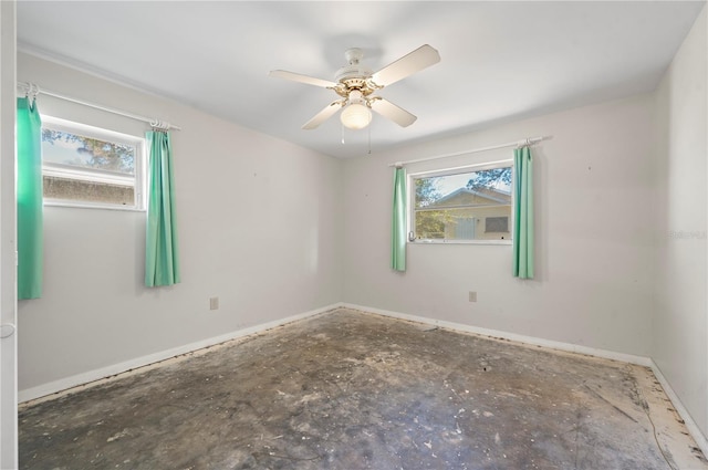 unfurnished room with ceiling fan and concrete flooring