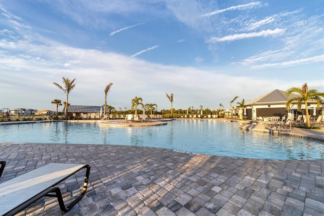 view of pool with a patio area and a water view