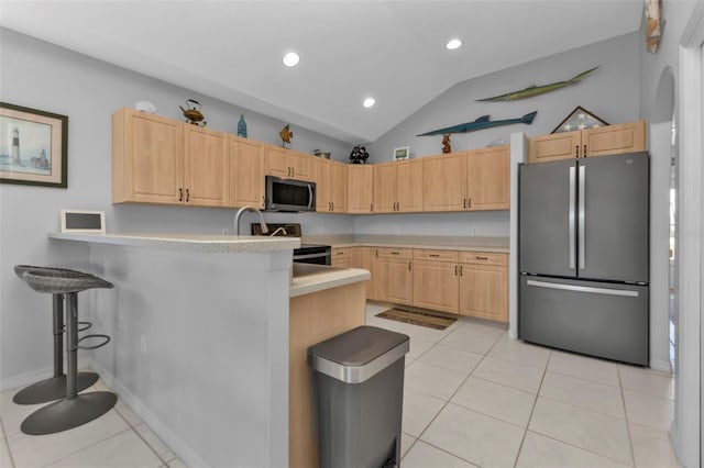 kitchen featuring lofted ceiling, a kitchen breakfast bar, light brown cabinetry, kitchen peninsula, and stainless steel appliances