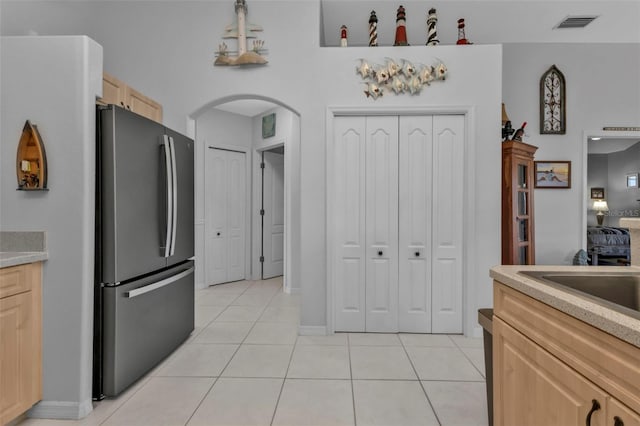 kitchen featuring light brown cabinets, light tile patterned floors, sink, and stainless steel refrigerator