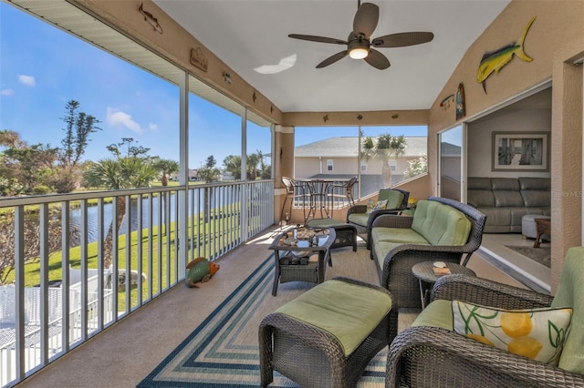 sunroom with ceiling fan and a water view