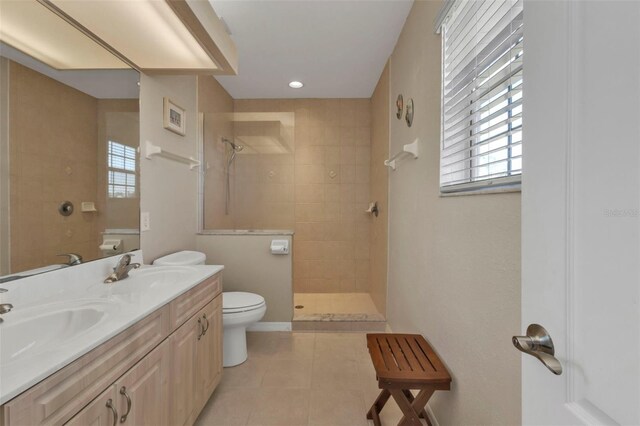 bathroom featuring tile patterned floors, vanity, a tile shower, and toilet