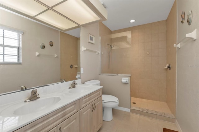 bathroom with tile patterned floors, vanity, a tile shower, and toilet