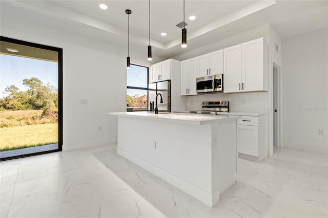 kitchen featuring white cabinetry, a kitchen island with sink, decorative light fixtures, and appliances with stainless steel finishes