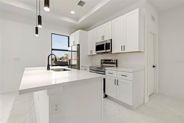 kitchen featuring pendant lighting, sink, stainless steel appliances, and an island with sink