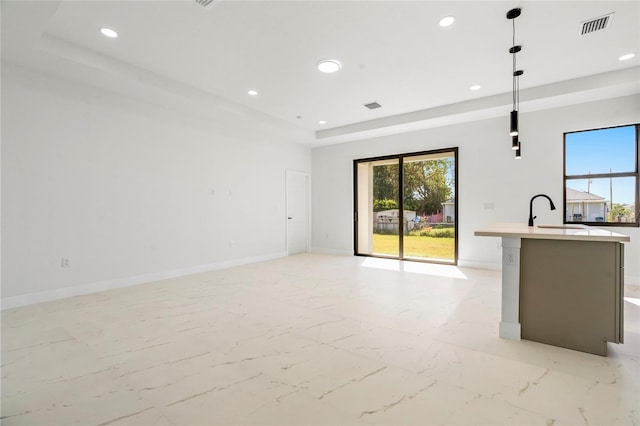 unfurnished living room featuring a raised ceiling and sink