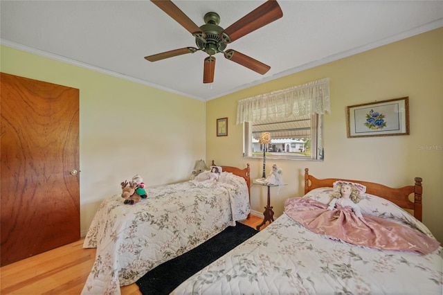 bedroom featuring hardwood / wood-style floors, ceiling fan, and crown molding