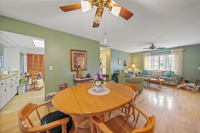 dining area with a skylight, light hardwood / wood-style flooring, ceiling fan, and sink