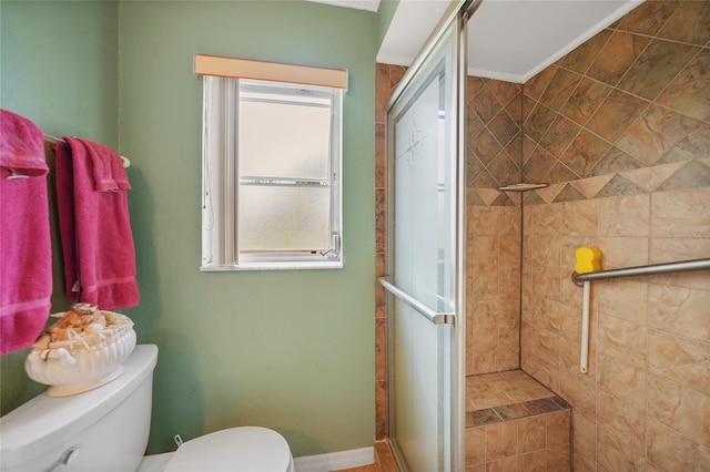 bathroom featuring toilet, a shower with shower door, and crown molding