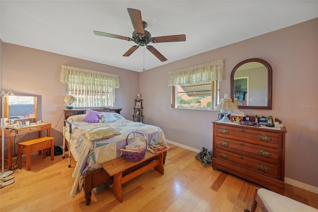 bedroom with ceiling fan, light hardwood / wood-style flooring, and multiple windows