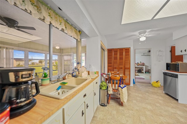 kitchen featuring ceiling fan, sink, white cabinets, and stainless steel appliances