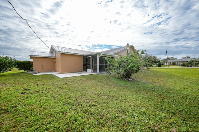 back of property featuring a sunroom, a patio area, and a lawn