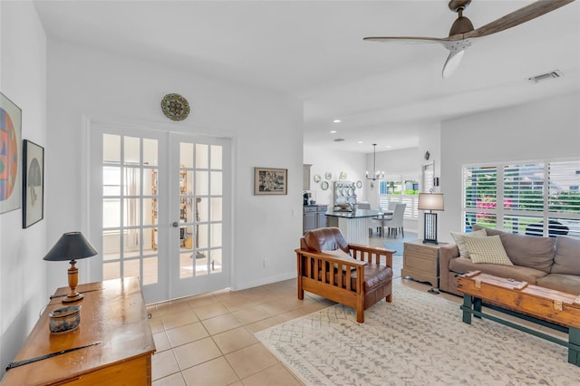 tiled living room with french doors and ceiling fan with notable chandelier