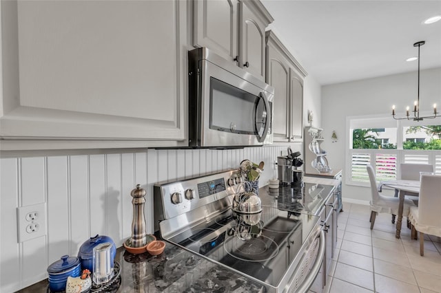 kitchen featuring gray cabinets, light tile patterned flooring, stainless steel appliances, and an inviting chandelier